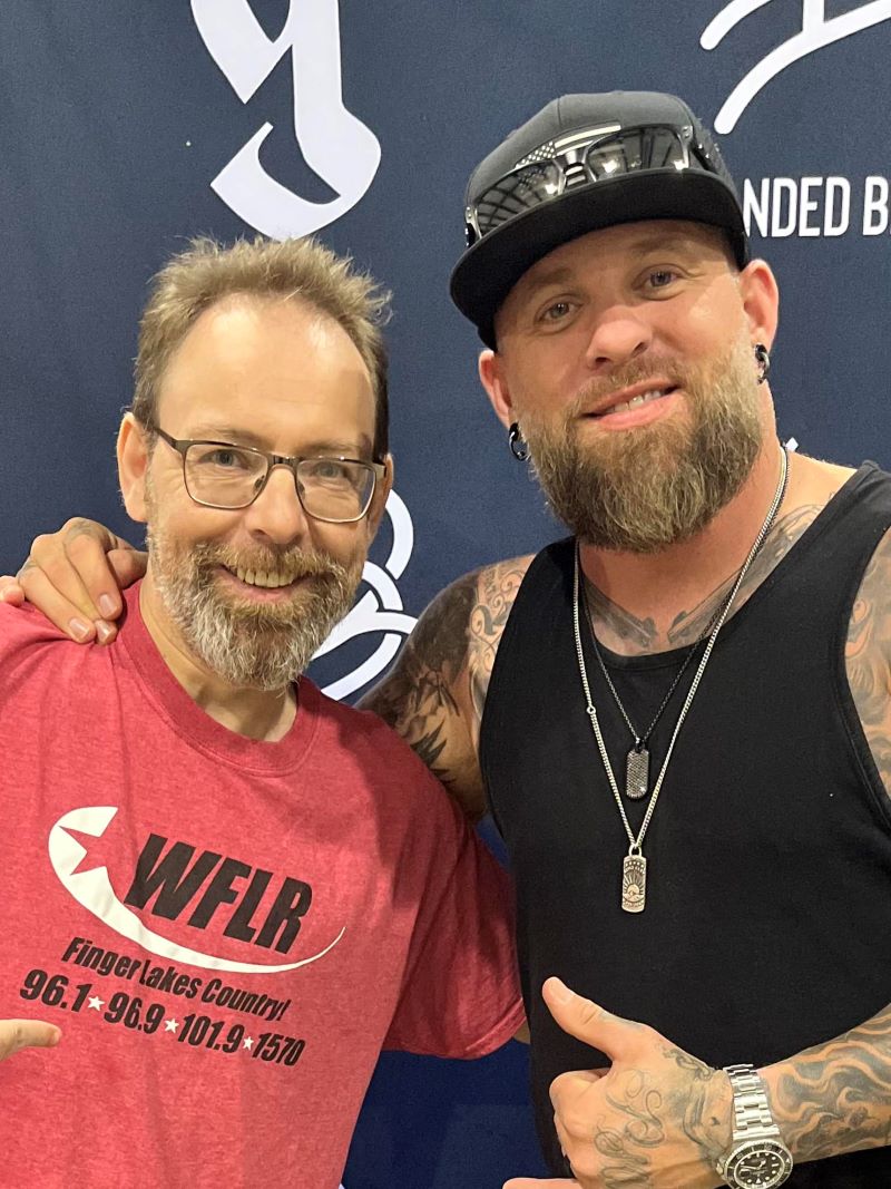 Man in red WFLR shirt with glasses poses next to a tattooed man in a black tank top and cap, with a "Branded Country" banner.