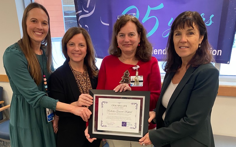 Four women hold a framed certificate in front of a '95 Years' banner at Rochester General Hospital.