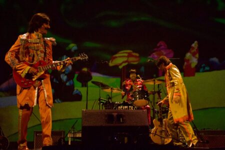 A Beatles tribute band performs on stage with "Yellow Submarine" backdrop imagery at a Finger Lakes venue.