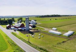 Aerial view of Christiansen Farm with red barn, tall silo, other buildings, fields, and a road.
