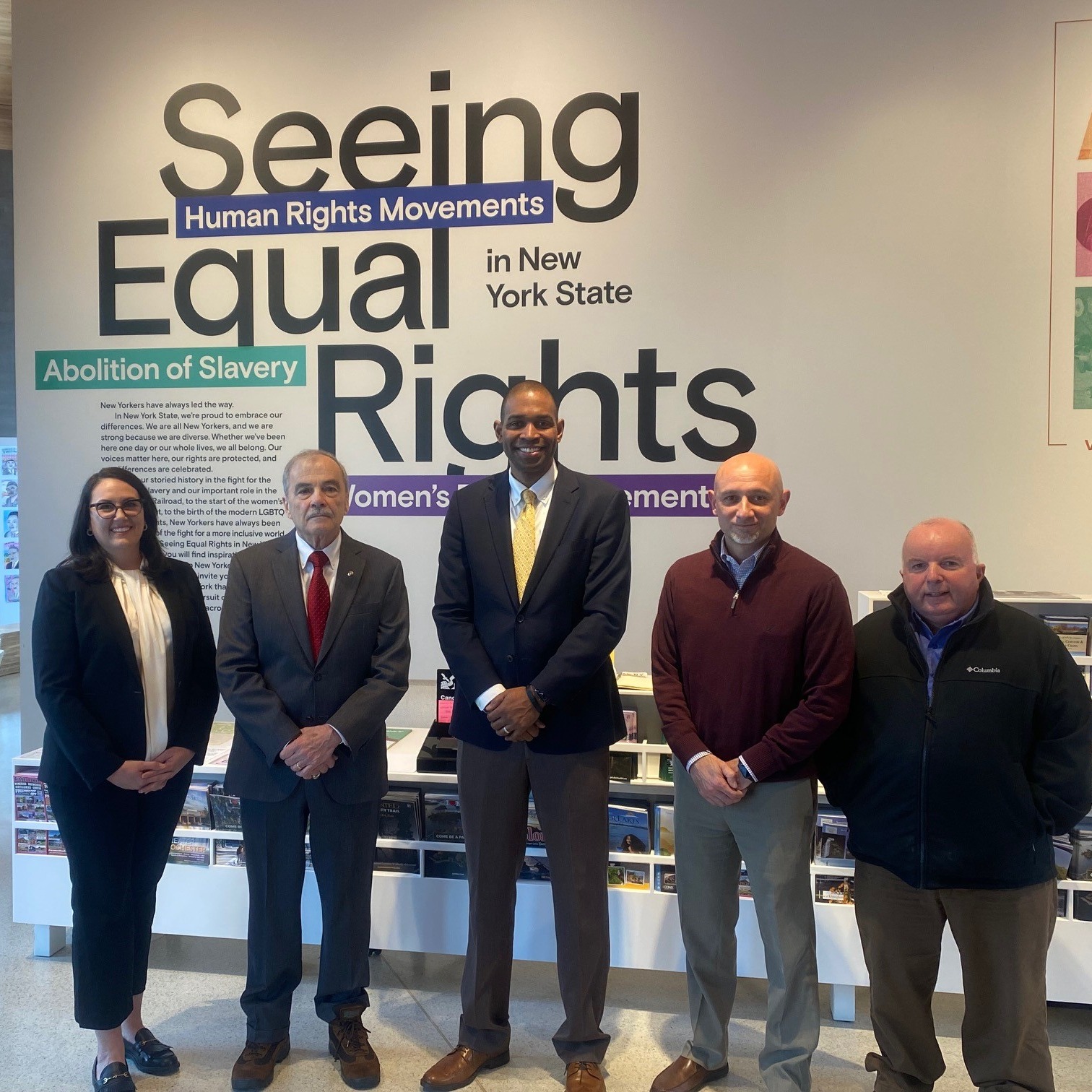 Lt. Governor Delgado and four others stand in front of a museum exhibit about human rights in New York State.