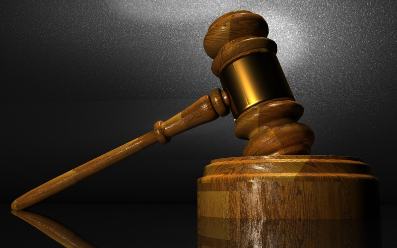 A wooden court gavel rests on a sound block, symbolizing justice and law.