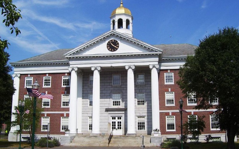 Auburn City Hall, a brick building with white columns, a clock tower, and a golden dome, under a blue sky.