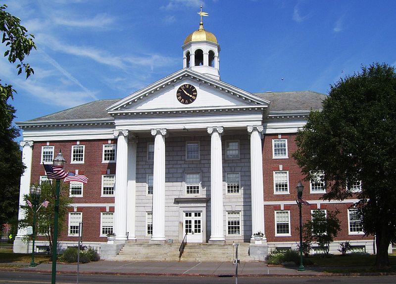Auburn City Hall, a brick building with white columns, a clock, and a golden dome, under a blue sky.