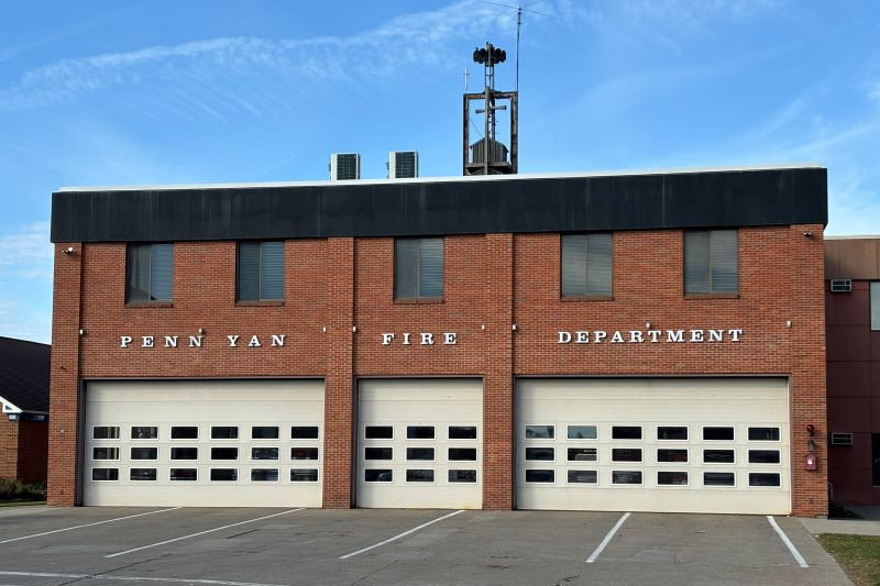 Exterior of the Penn Yan Fire Department, a brick building with three garage bays and a bell tower.