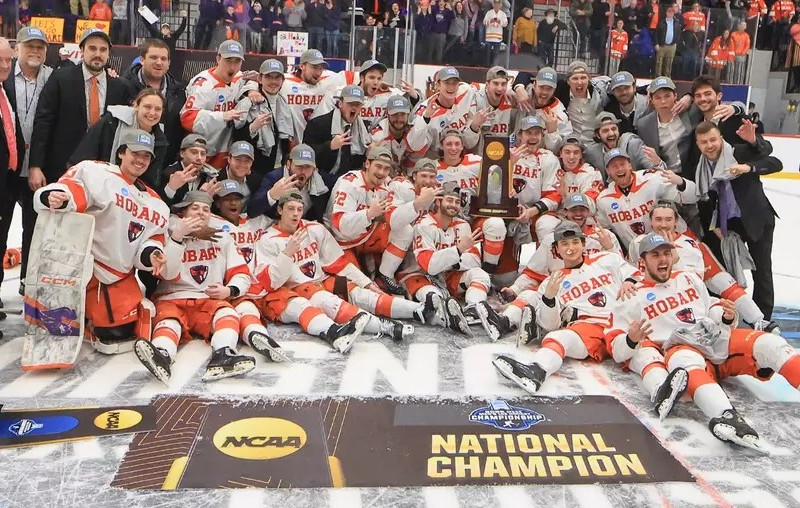 The Hobart College hockey team celebrates their NCAA National Championship victory on the ice with the trophy.