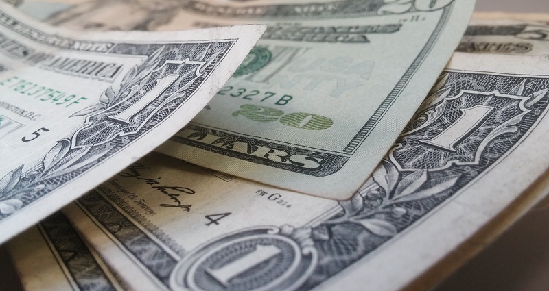 Close-up of US dollar bills, including ones and a twenty, on a flat surface.