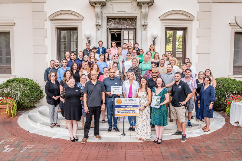 A large group poses on steps outside Geneva On The Lake during a Finger Lakes Chamber networking mixer.