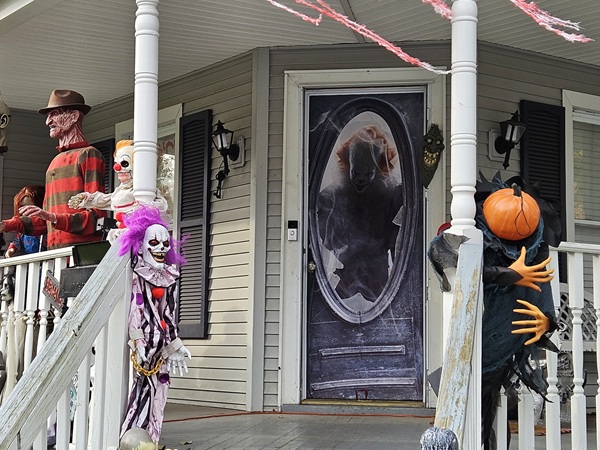 House porch decorated for Halloween with Freddy Krueger, Pennywise, clowns, and a pumpkin monster.