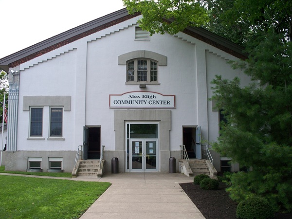 Exterior of the Alex Eligh Community Center, a white building with open doors and a prominent sign.