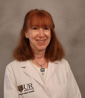 Sara Miller, a woman with red hair, smiles in a white lab coat with a UR Medicine Finger Lakes Health logo.