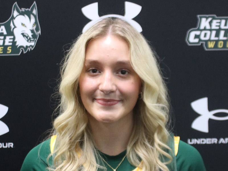 Keuka College athlete Burd smiles in front of a black backdrop with school and Under Armour logos.