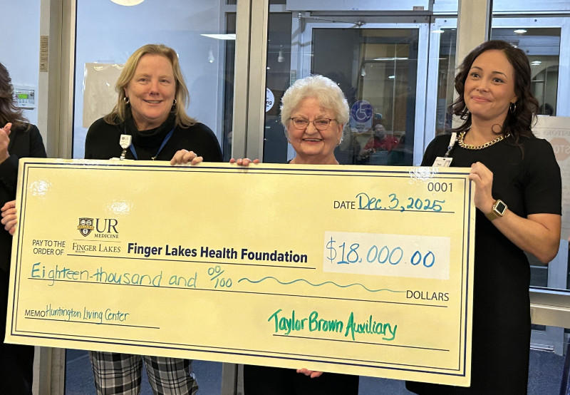 Three women hold a large check for $18,000 from Taylor Brown Auxiliary to Finger Lakes Health Foundation.
