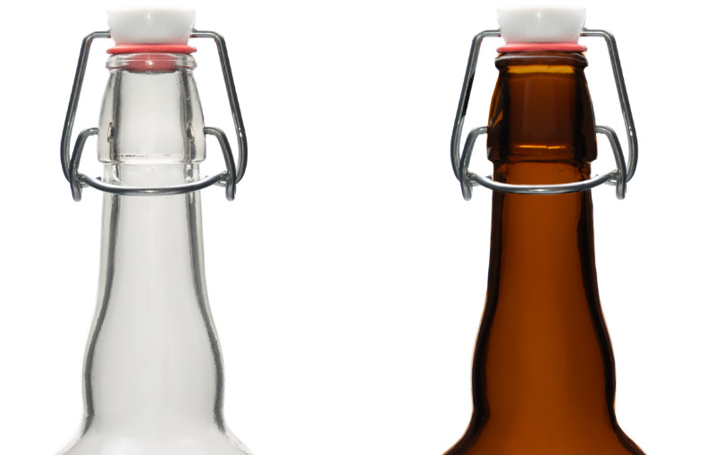 Close-up of clear and brown glass bottles with swing-top closures and white ceramic caps on a white background.