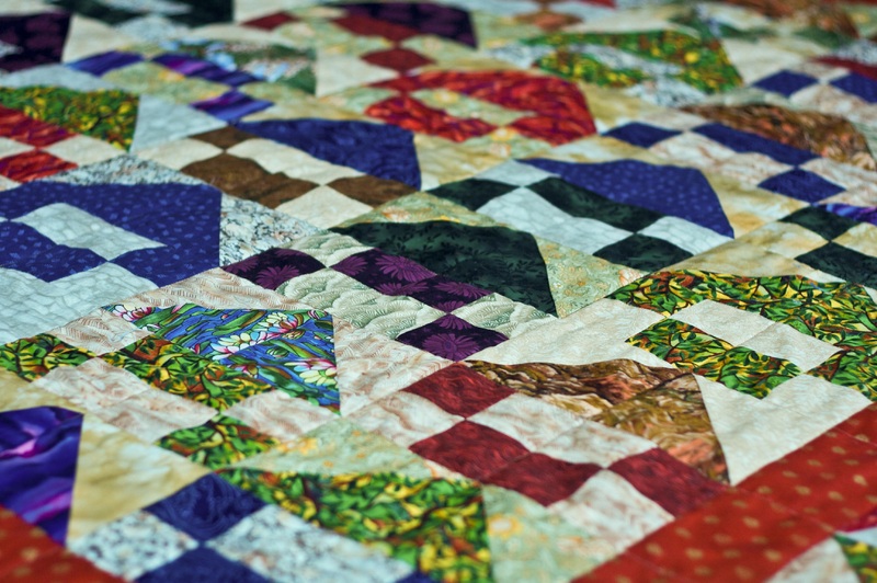 Close-up of a colorful patterned quilt with geometric triangles and diamonds.