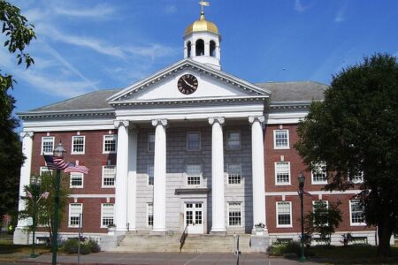 Auburn City Hall, a brick building with white columns and a golden-domed clock tower, under a blue sky.