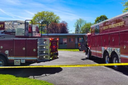 Two Auburn Fire Department trucks parked outside a nursing home with yellow caution tape in the foreground.