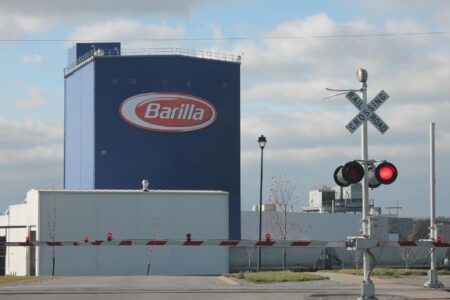 The Barilla pasta manufacturing facility in Avon, New York, with a railroad crossing signal and barrier.