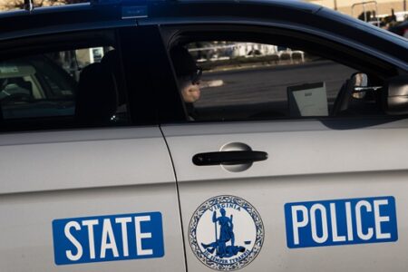 Side view of a Virginia State Police patrol car with 'STATE POLICE' and the state seal visible on the door.