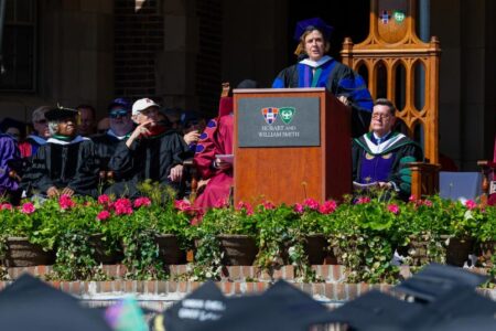 A woman in academic regalia speaks at a podium during Hobart and William Smith Colleges commencement.
