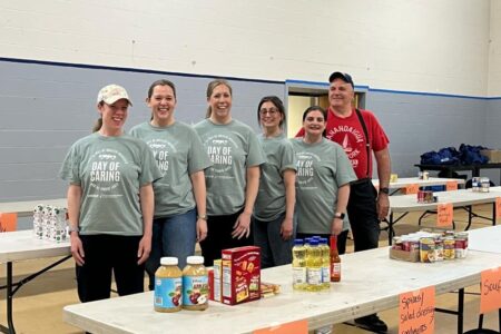 Volunteers from Ontario and Wayne Counties' Day of Caring event stand with donated food items at a distribution site.