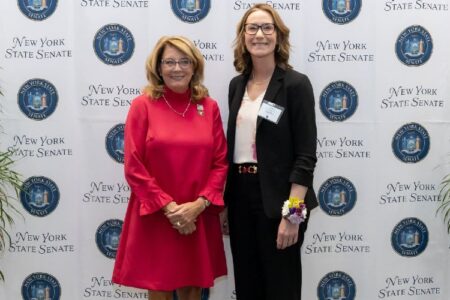 Senator Helming (left) honors Megan Freida (right) as Woman of Distinction at a New York State Senate event.