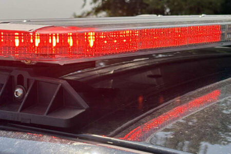 Close-up of flashing red emergency lights on a police car, reflecting on the vehicle's roof.