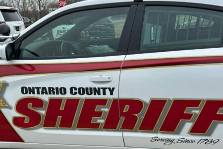 Side view of an Ontario County Sheriff patrol car with red and gold lettering and a light bar on the roof.