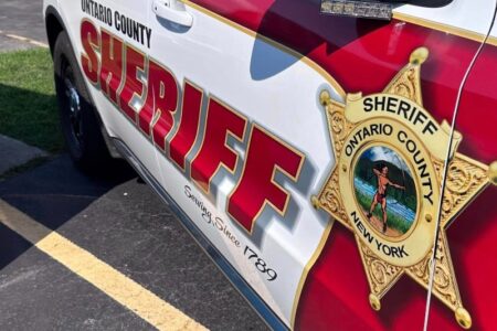 Side view of an Ontario County Sheriff's patrol car with its emblem visible.