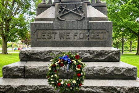 A stone monument with 'Lest We Forget' carved into it, adorned with a Memorial Day wreath.