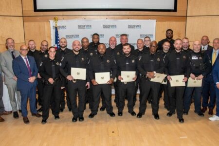 Group of Rochester Regional Health Peace Officer graduates holding certificates at a ceremony.