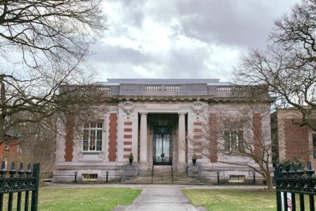 Exterior view of the Seymour Library in Auburn, New York, a classical stone building with bare trees under a cloudy sky.