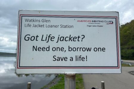 A sign for the Watkins Glen Life Jacket Loaner Station by America's Boating Club, encouraging borrowing life jackets.
