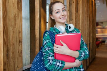 Smiling college student with a backpack and folder, representing financial aid access.