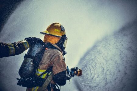 Firefighter in full gear sprays water from a hose to extinguish a shed fire in Yates County.