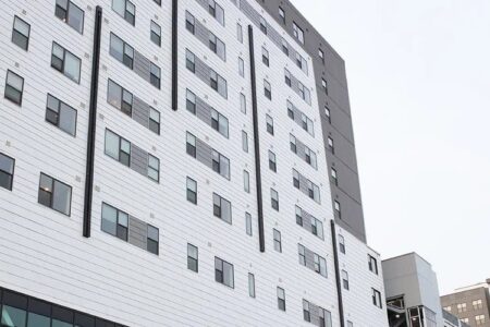 Modern white and grey multi-story building with many windows, known as the Asteri building in Ithaca.
