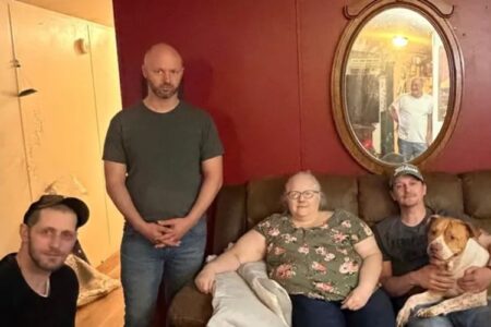 Family and friends gather indoors, with a man holding a dog on a couch, likely for a fundraiser.