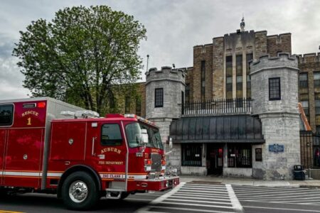 A red Auburn Fire Department rescue truck parked outside the Auburn Correctional Facility under an overcast sky.