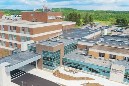 Aerial view of Newark-Wayne Community Hospital, a modern brick and glass building with a large parking lot and green landscape.