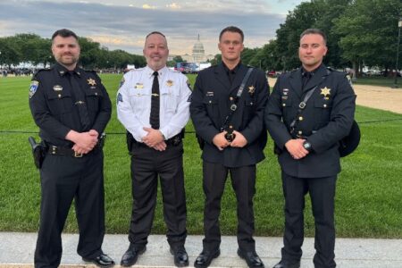 Four Ontario County officers in uniform stand outdoors with the U.S. Capitol building in the background.