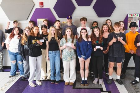 Group of Clyde-Savannah teens holding certificates after completing a mental health program in a school hallway.