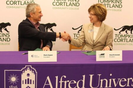 Alfred University President Mark Zupan and TC3 President Amy Krsmanick shake hands at a partnership signing ceremony.