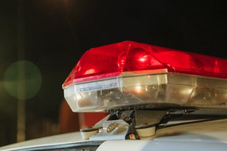 Close-up of a police car's red and clear emergency lights flashing at night.