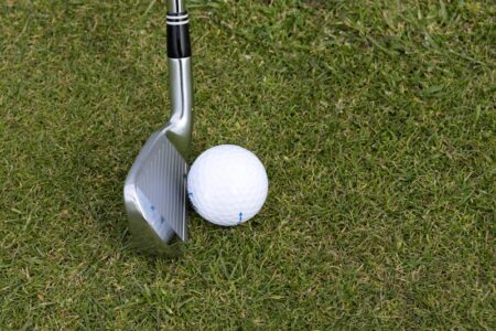 A golf club and a golf ball rest on green grass.