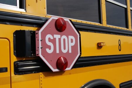 A close-up of a yellow school bus with its red stop sign extended.
