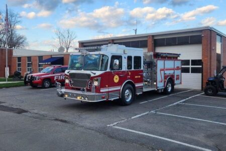 Watkins Glen Fire Department's red and white fire truck parked outside the station with another emergency vehicle.
