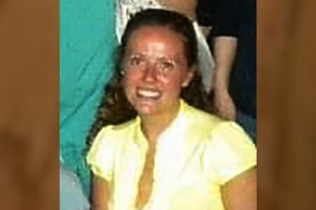 Christine Banfield, smiling, with long dark hair and a yellow shirt.