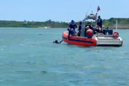 US Coast Guard boat with crew on blue water, one person in water, during search for Lynette Hooker in Bahamas.