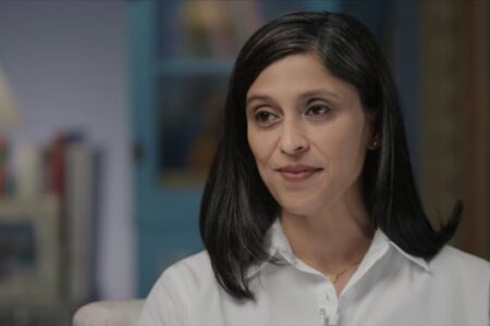Usha Vance, with dark hair and a white shirt, smiles subtly while discussing the summer reading challenge.