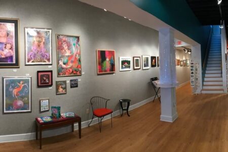Interior view of the Arts Center of Yates County gallery, featuring colorful framed artworks on display.